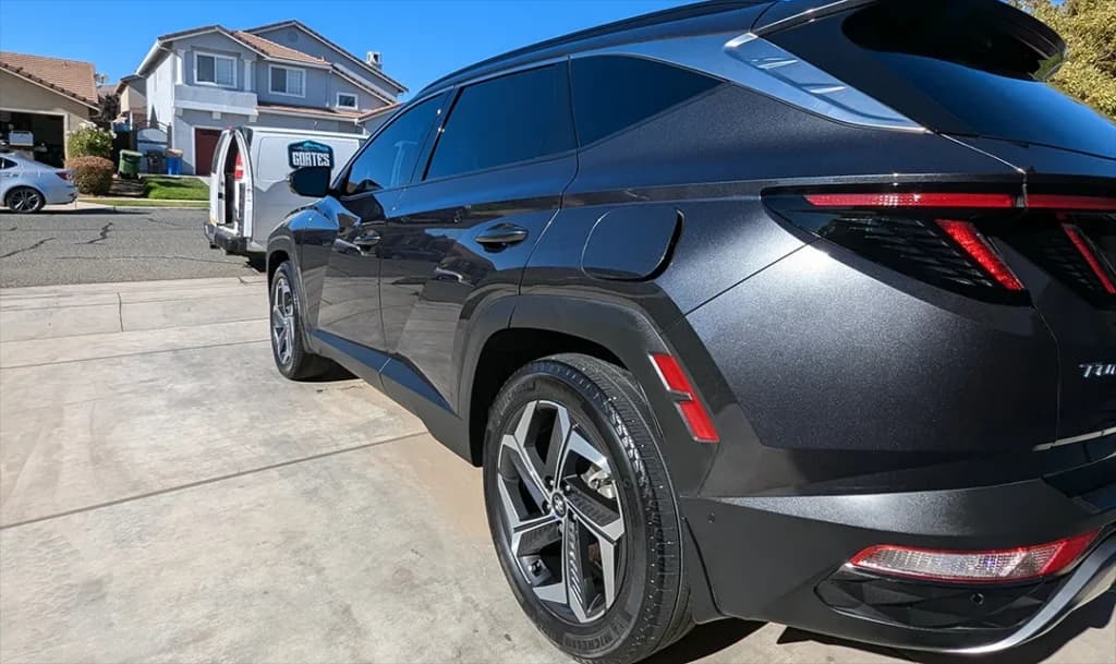 Dark gray Hyundai Tucson after a full detail, with the Cortes Express van in the driveway behind it