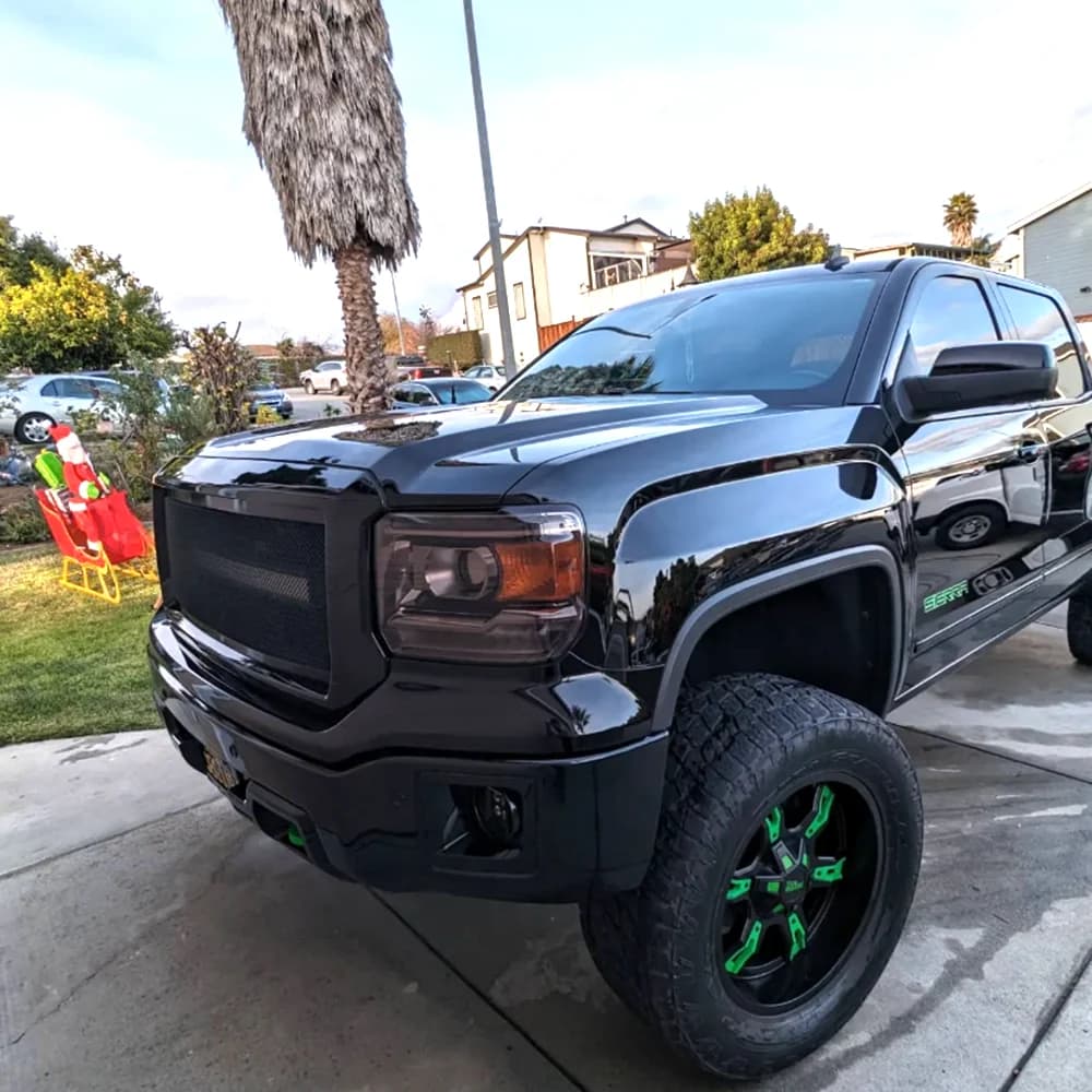 Black GMC Sierra pickup with green-accent wheels after a detail